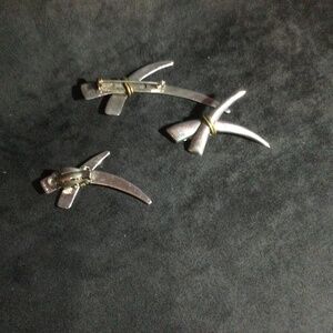 A brooch and a pair of silver colored earrings.